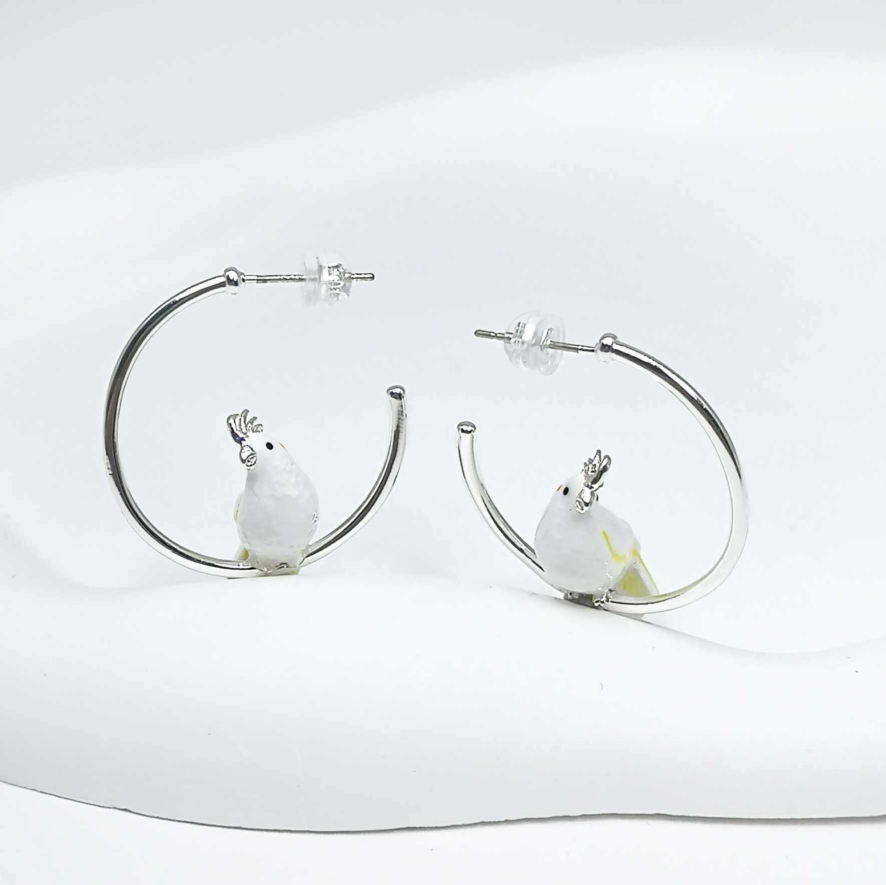 Hoop earrings with bird charms on a white background