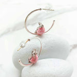 Earrings with pink bird charms on a white background