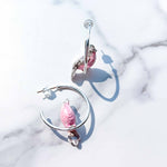 Pair of pink bird-shaped earrings on a marble surface
