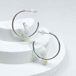 Silver-plated hoop earrings with white enamel cockatoo bird accents, a whimsical and chic statement for everyday wear