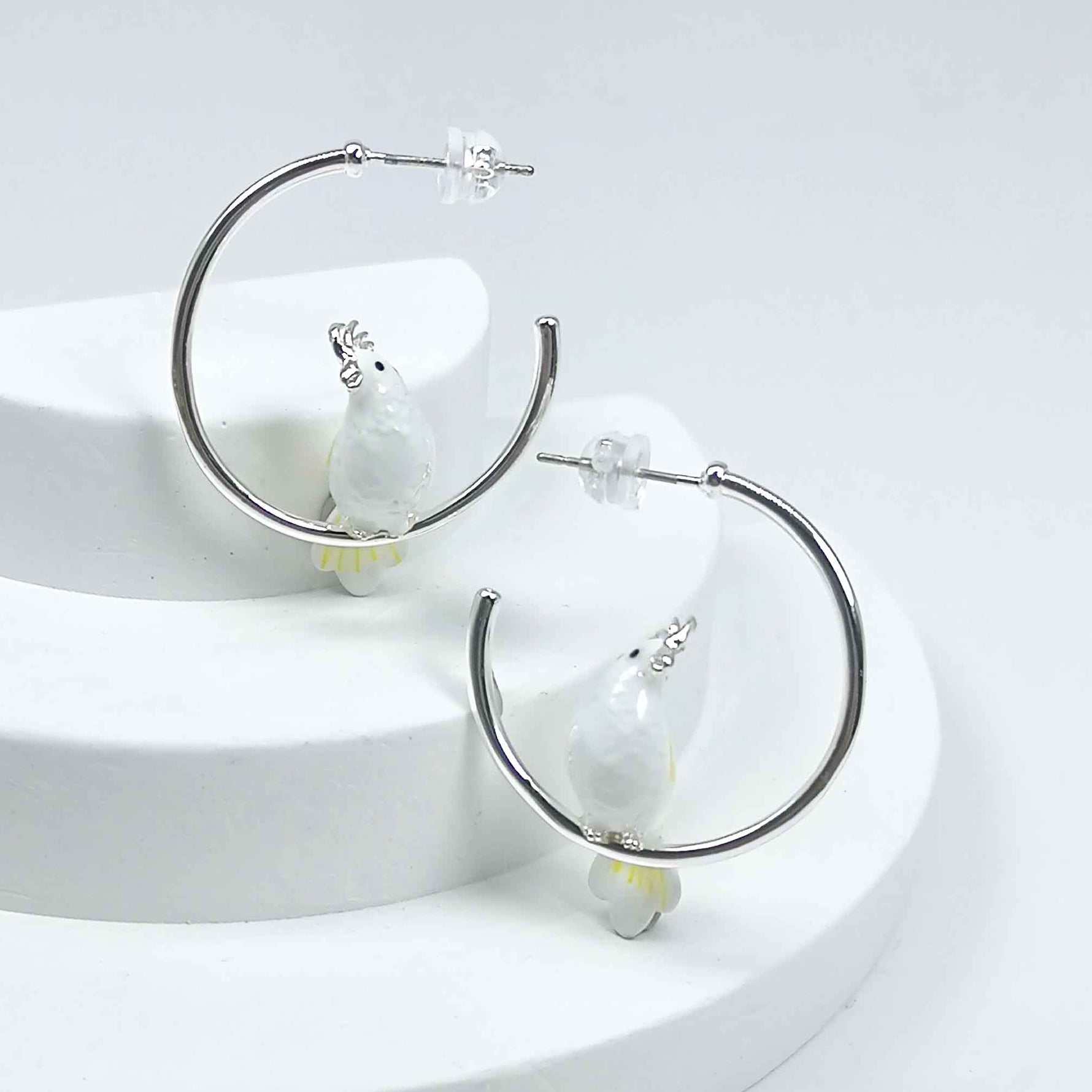 Silver-plated hoop earrings with white enamel cockatoo bird accents, a whimsical and chic statement for everyday wear