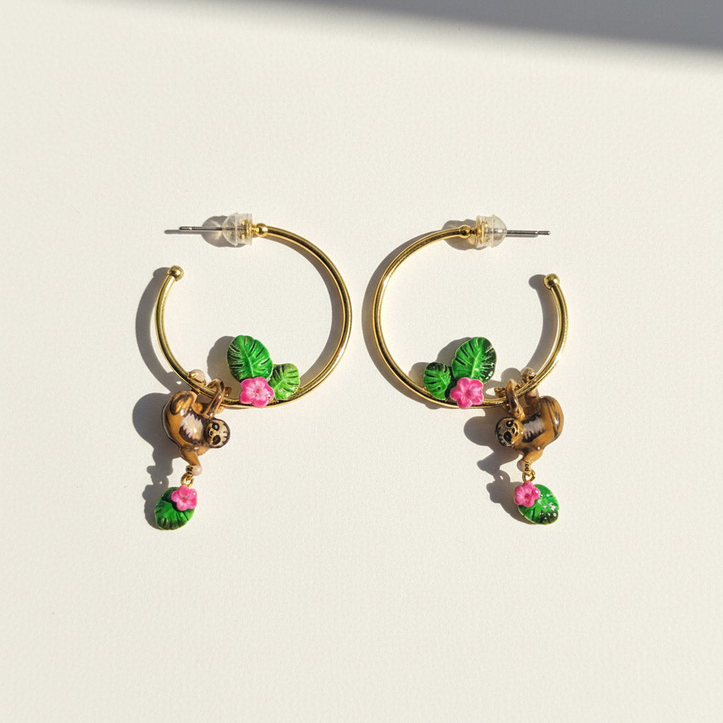 Gold hoop earrings with floral charms on a light background