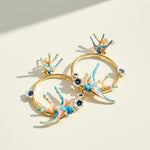 Gold hoop earrings with colorful bird designs on a light background