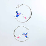Hoop earrings with hummingbird designs on a light gray background