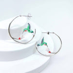 Hoop earrings with hummingbird design on a white background