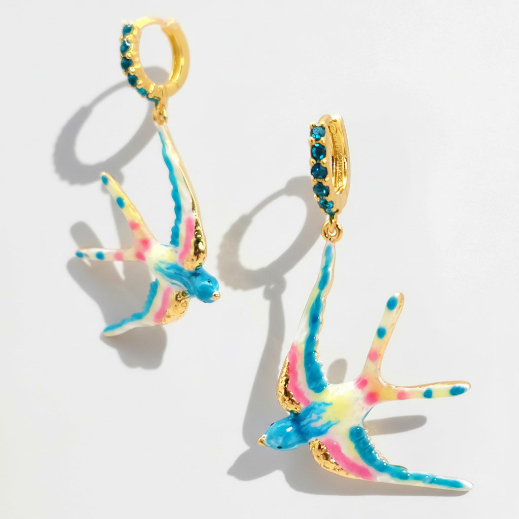 Colorful bird-shaped earrings with gold accents on a light gray background