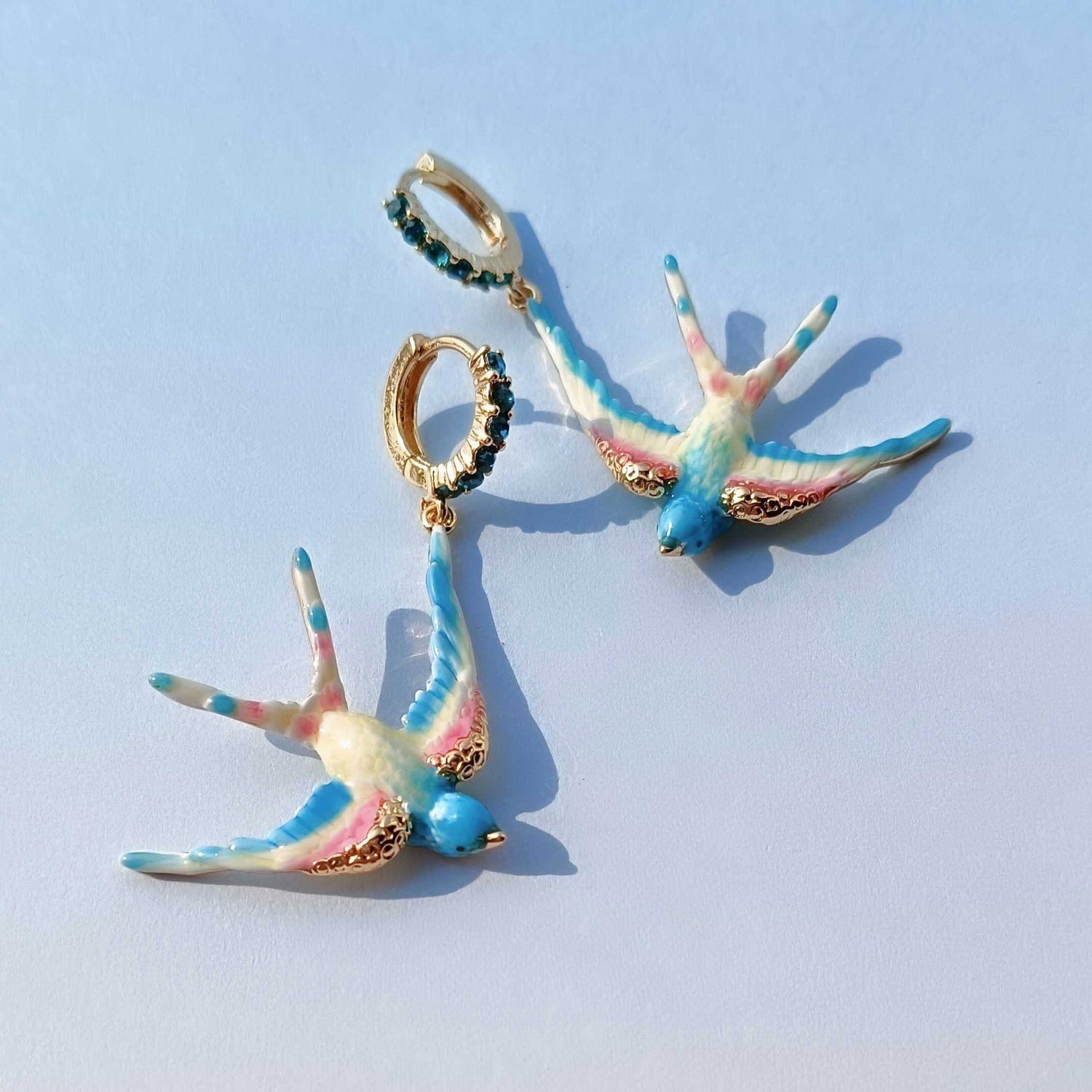 Colorful bird-shaped earrings on a light blue background