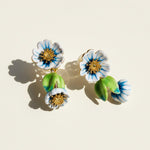 Floral earrings with blue, white, and green colors on a beige background