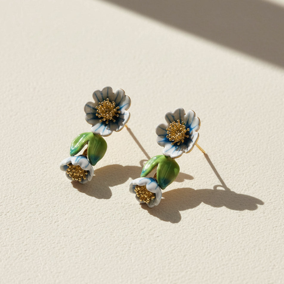 Floral earrings with green leaves and gold centers on a beige background
