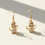 Teapot-shaped earrings with gold accents on a light background