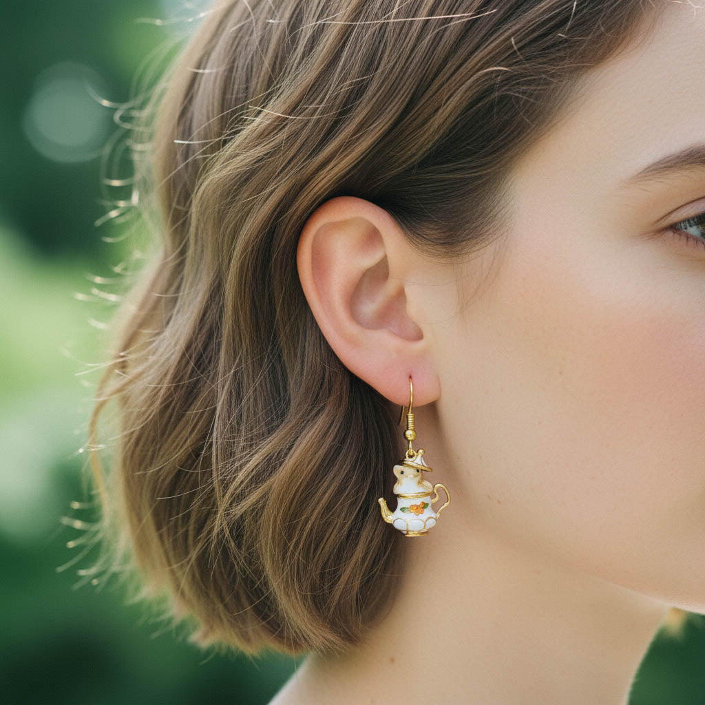 Close-up of a person wearing a gold and pearl earring with a blurred green background