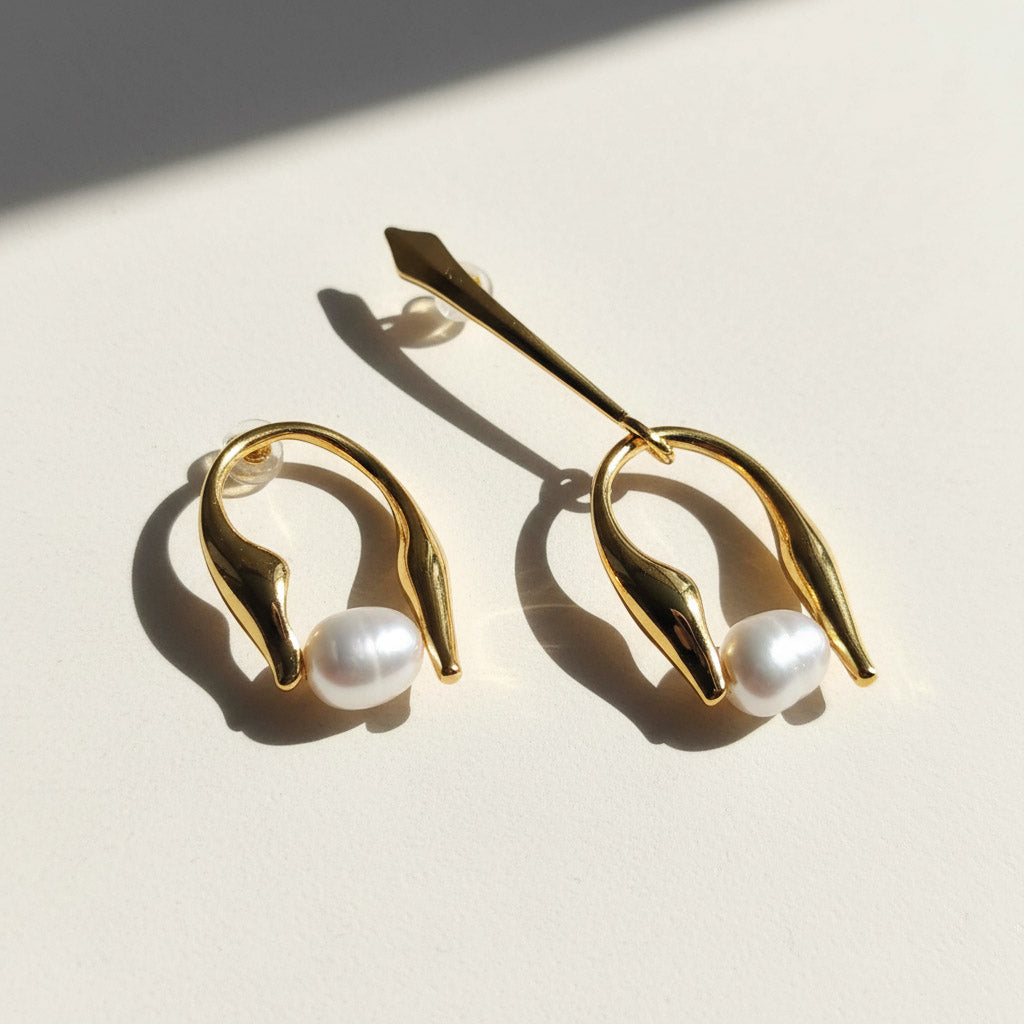 Gold earrings with pearls on a light background
