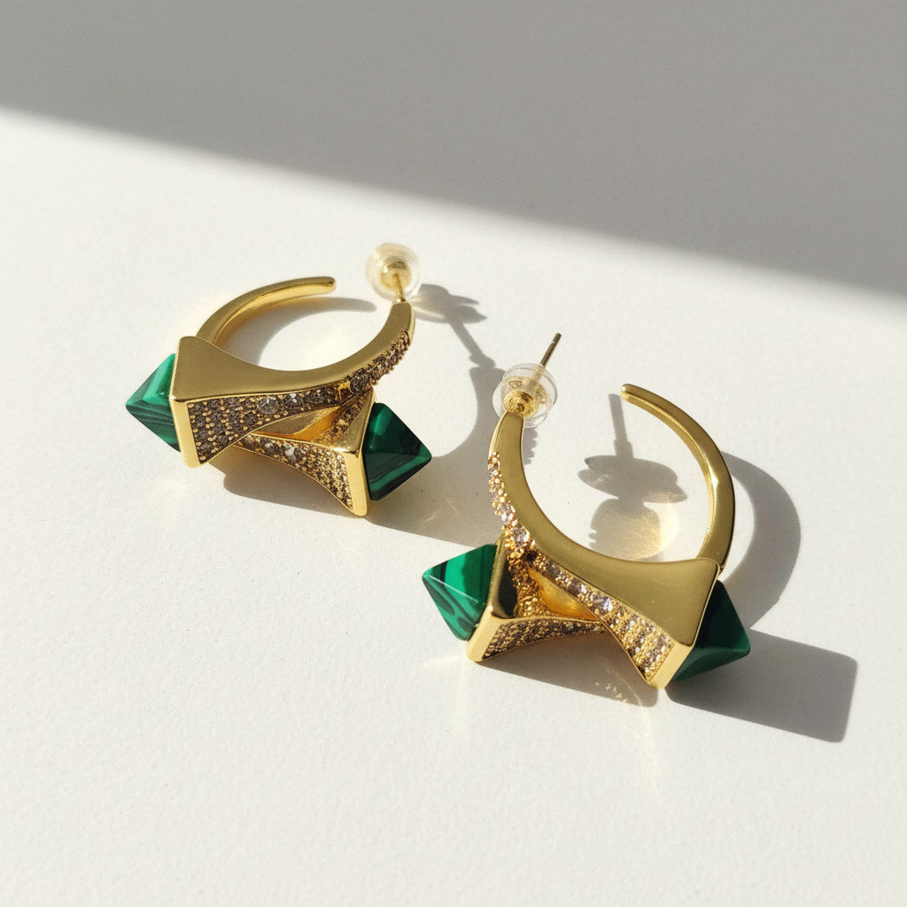 Gold and green earrings on a light background