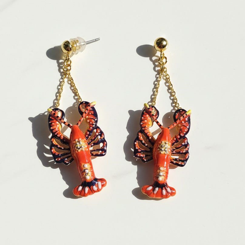 Lobster-shaped earrings with gold chains on a white background