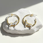 Gold hoop earrings with tiger designs on a white stone surface