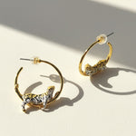 Gold hoop earrings with tiger designs on a light background