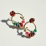 Gold hoop earrings with colorful floral and bird designs on a light background