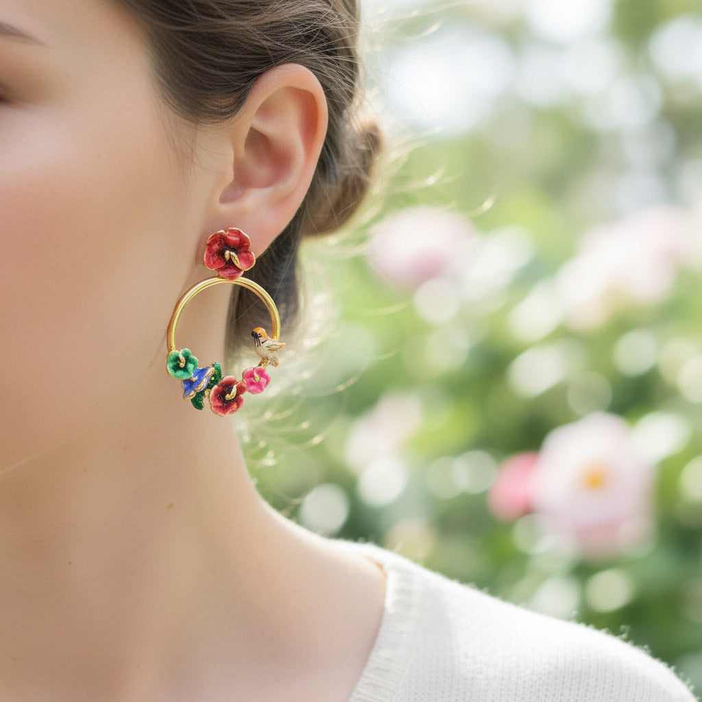 Close-up of a person wearing floral hoop earrings with a blurred natural background