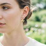 Close-up of a woman wearing floral earrings with a blurred natural background