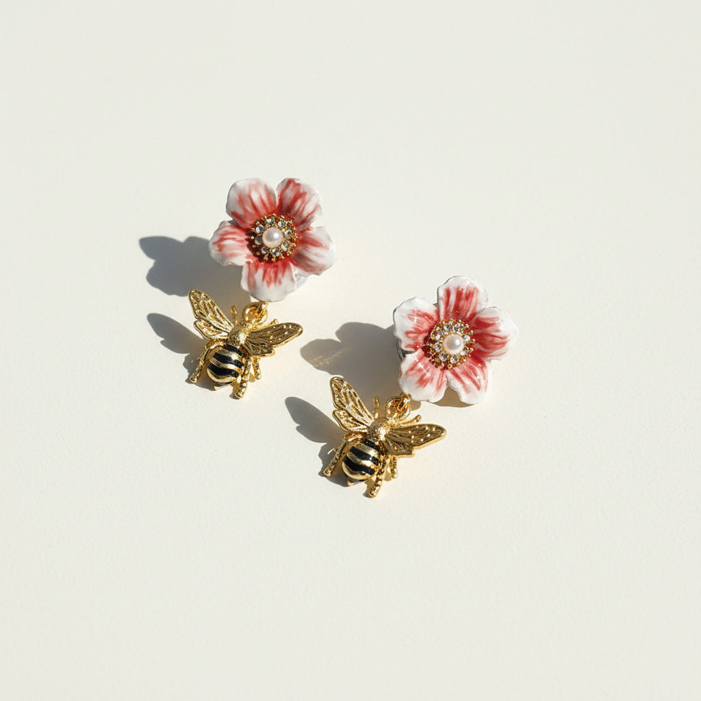 Pair of earrings with floral and bee designs on a light background