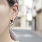 Close-up of an ear wearing a gold hoop earring with a cat design.