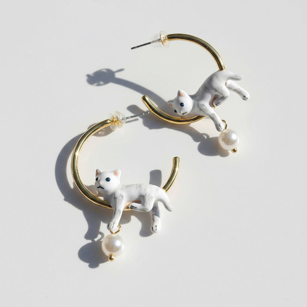 Cat-shaped earrings with gold loops on a light gray background