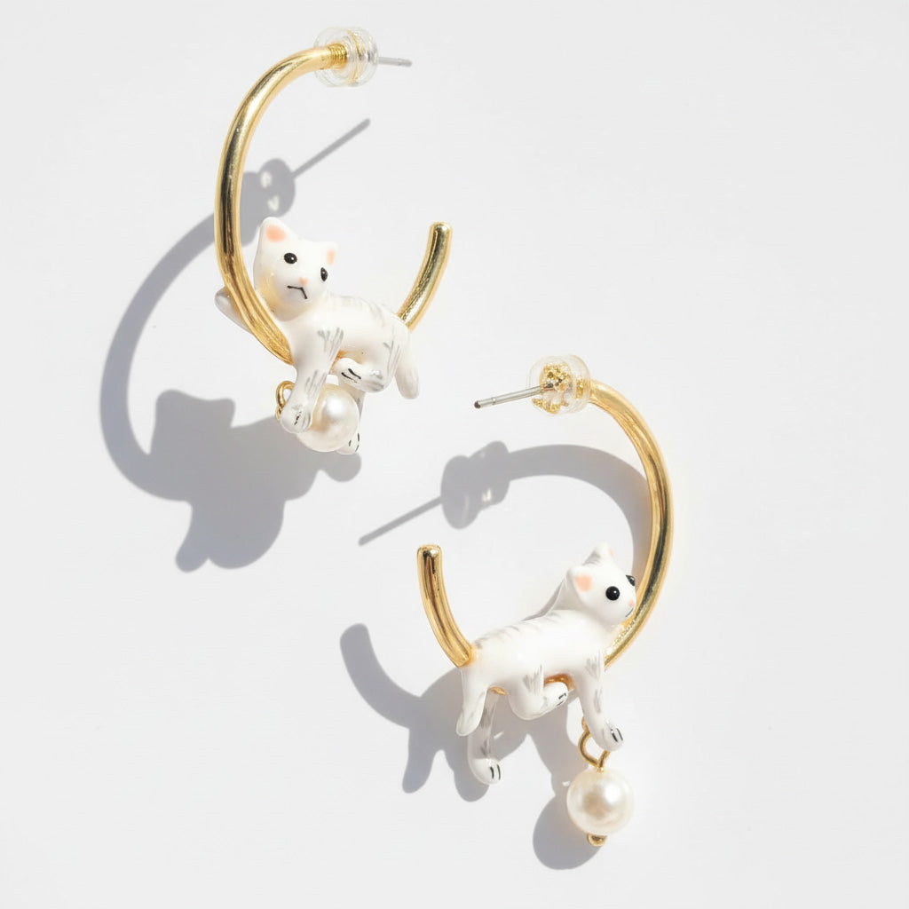 Gold hoop earrings with white animal figures and pearl accents on a light gray background
