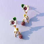 Pair of floral and grape earrings on a light purple background