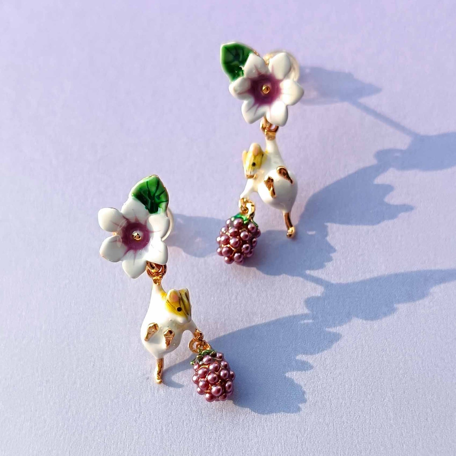Pair of floral and grape earrings on a light purple background
