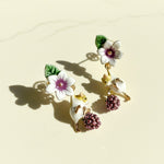 Floral and bird-themed earrings on a beige background