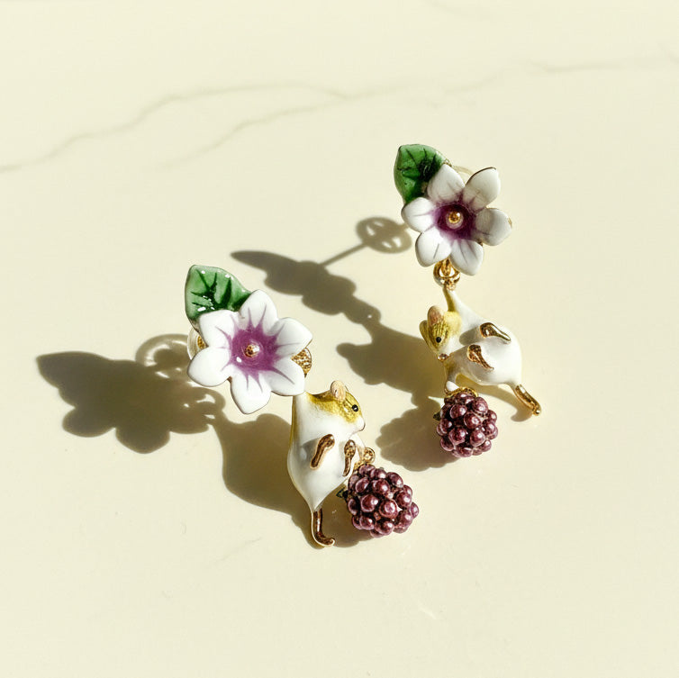 Floral and bird-themed earrings on a beige background