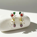 Pair of earrings with floral and mouse designs on a white stone surface