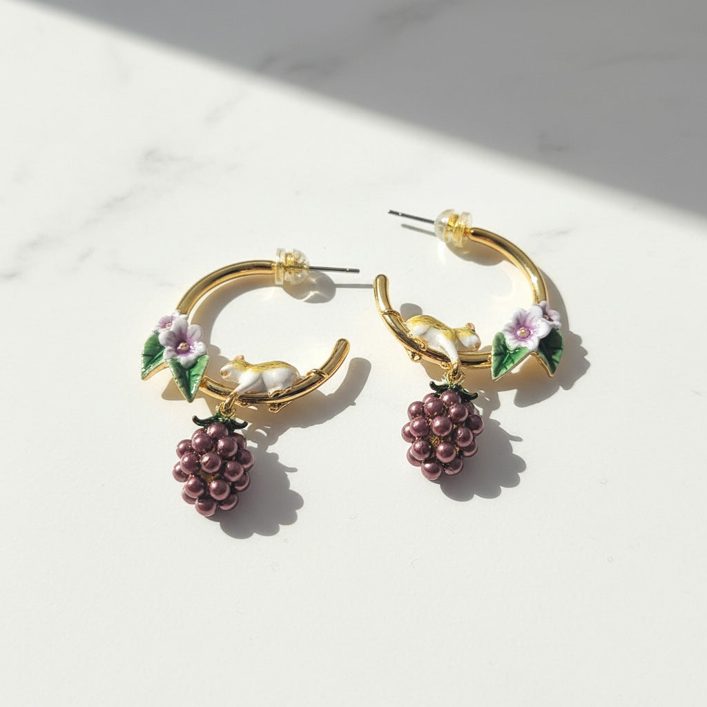 Gold hoop earrings with floral and berry designs on a light background