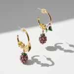 Gold hoop earrings with berry and mouse designs on a light gray background