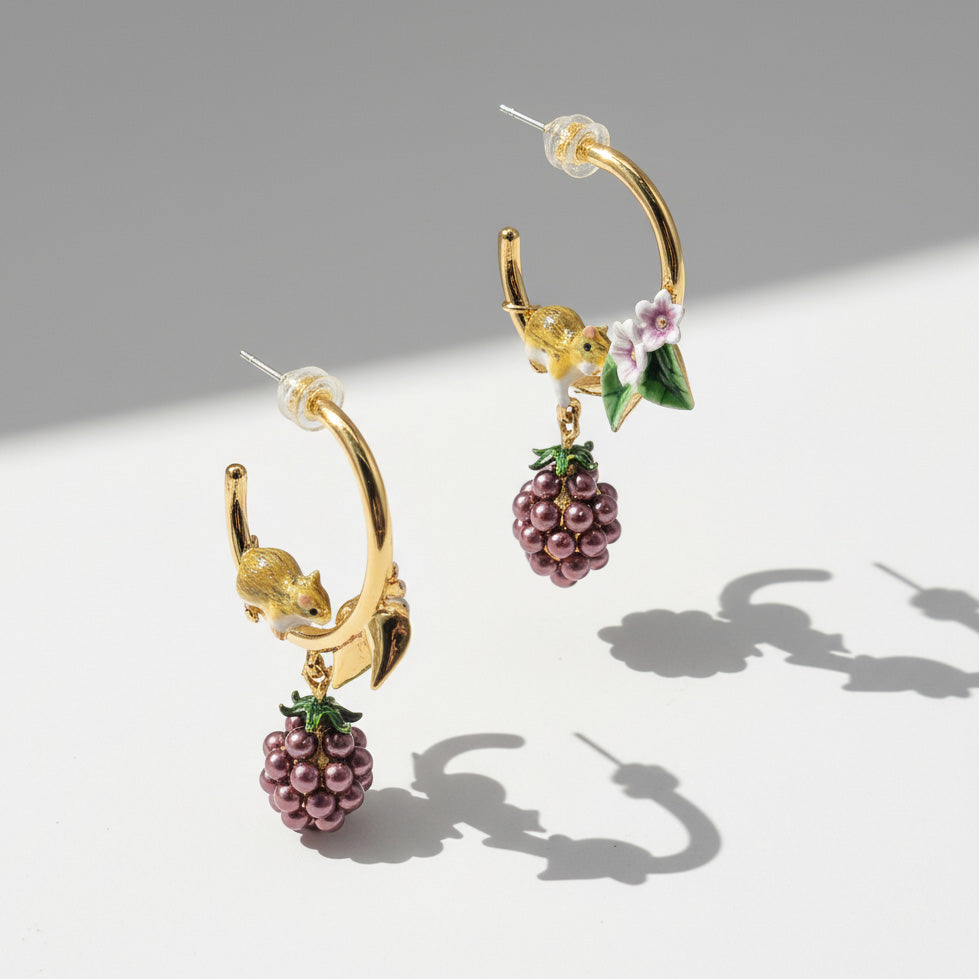 Gold hoop earrings with berry and mouse designs on a light gray background