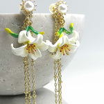 Floral earrings with gold chains on a textured surface