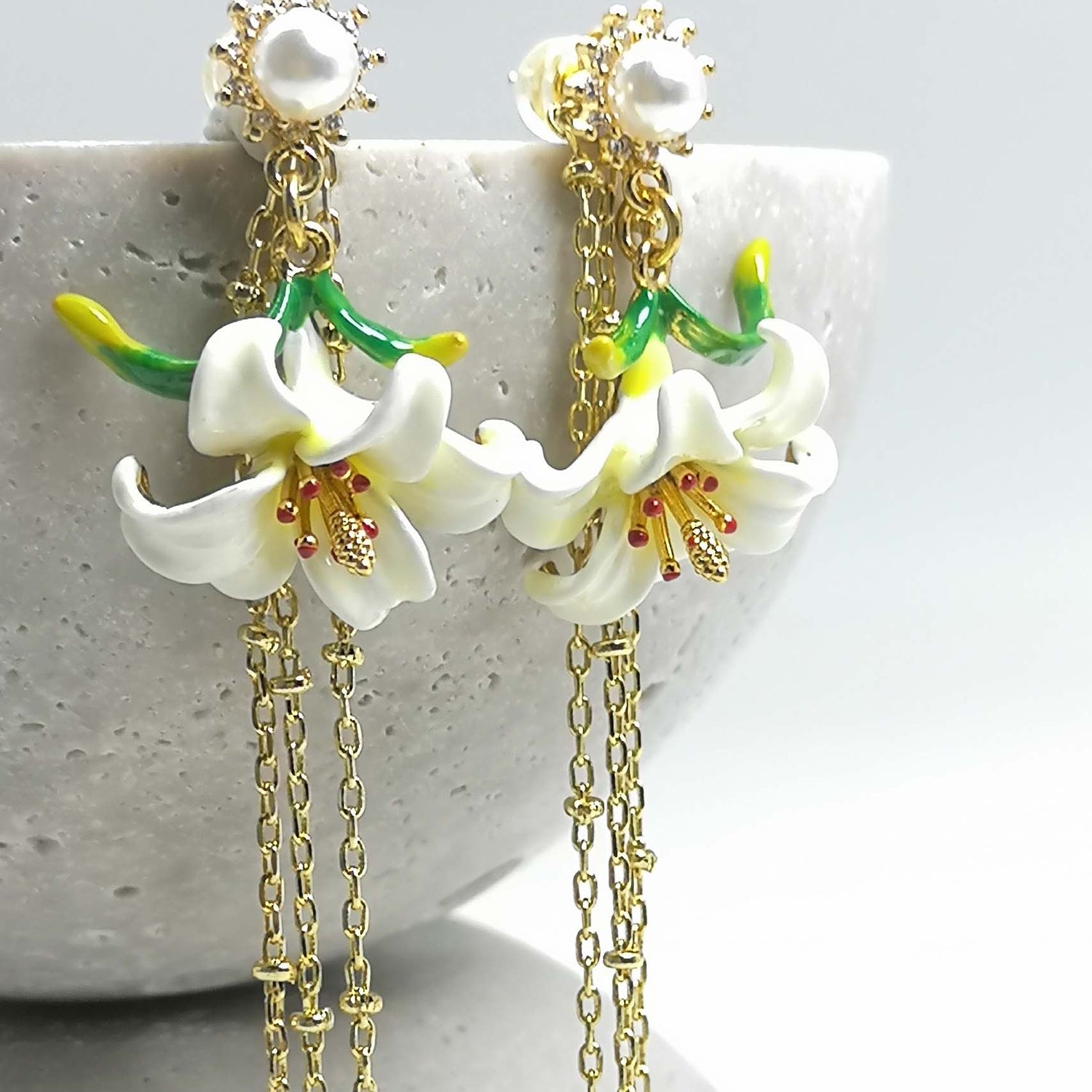 Floral earrings with gold chains on a textured surface
