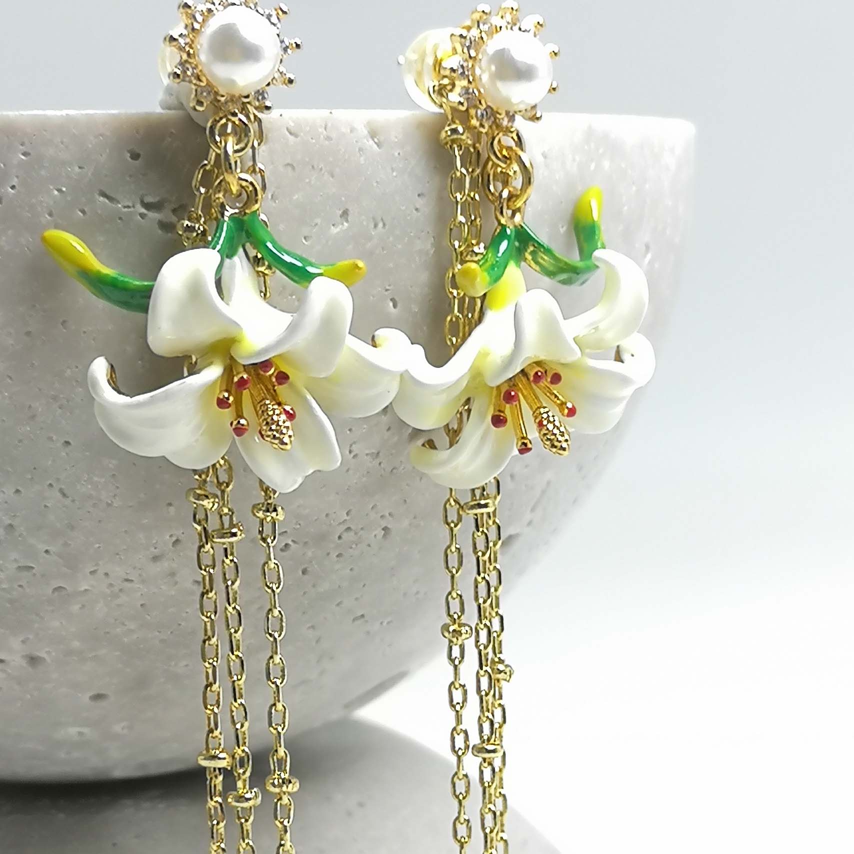 Floral earrings with gold chains on a textured surface