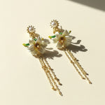 Floral earrings with gold chains on a beige background