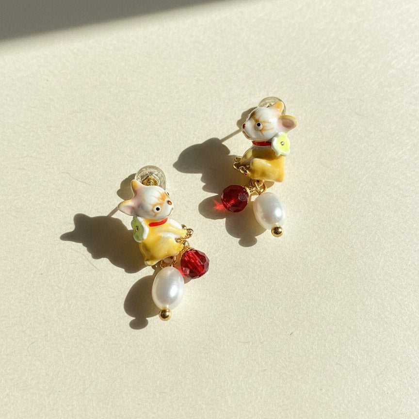 Pair of earrings with cartoon character design on a beige background