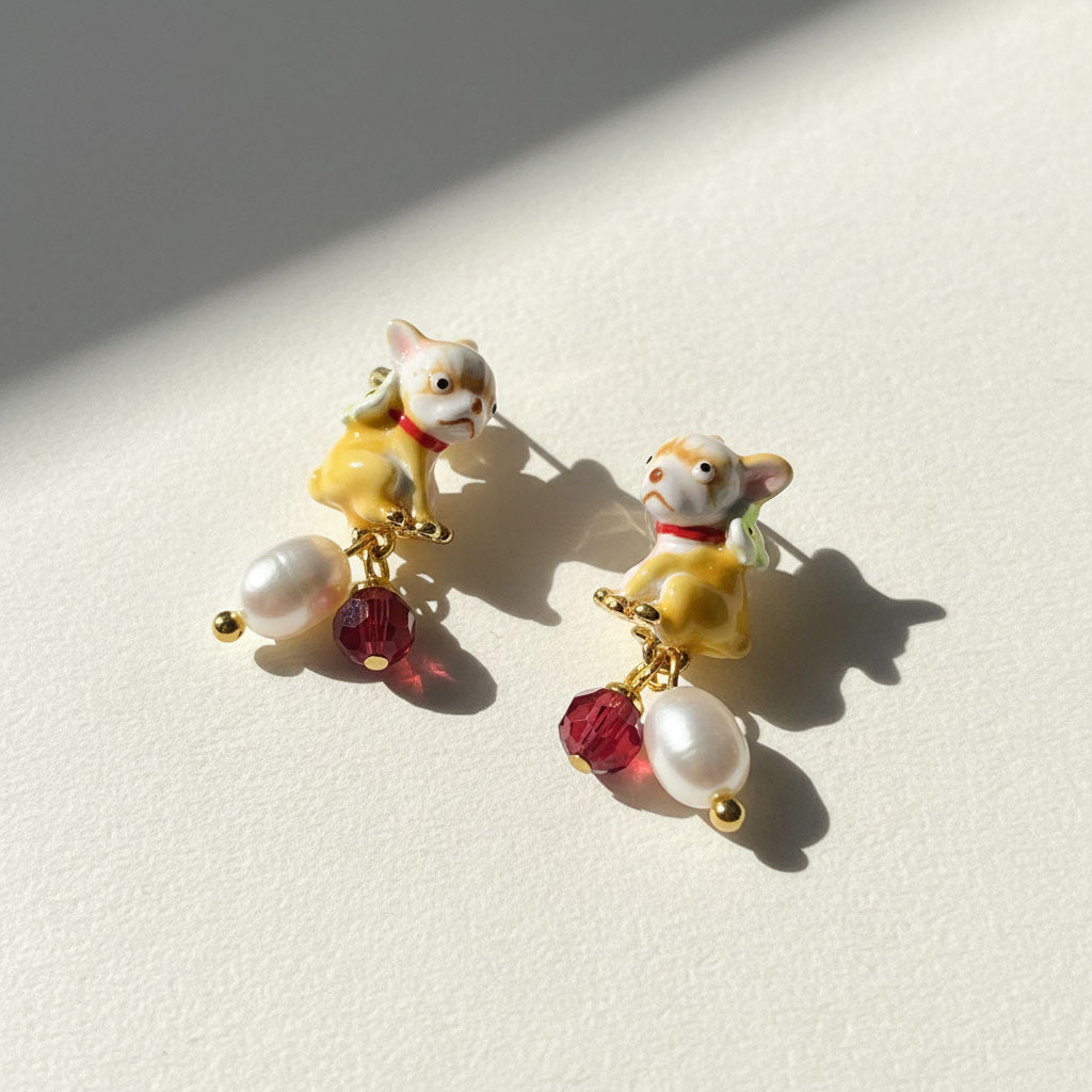 Pair of earrings with dog figures and pearl-like beads on a light background