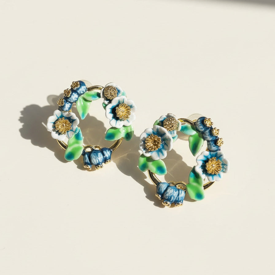 Floral hoop earrings with blue and green flowers on a beige background