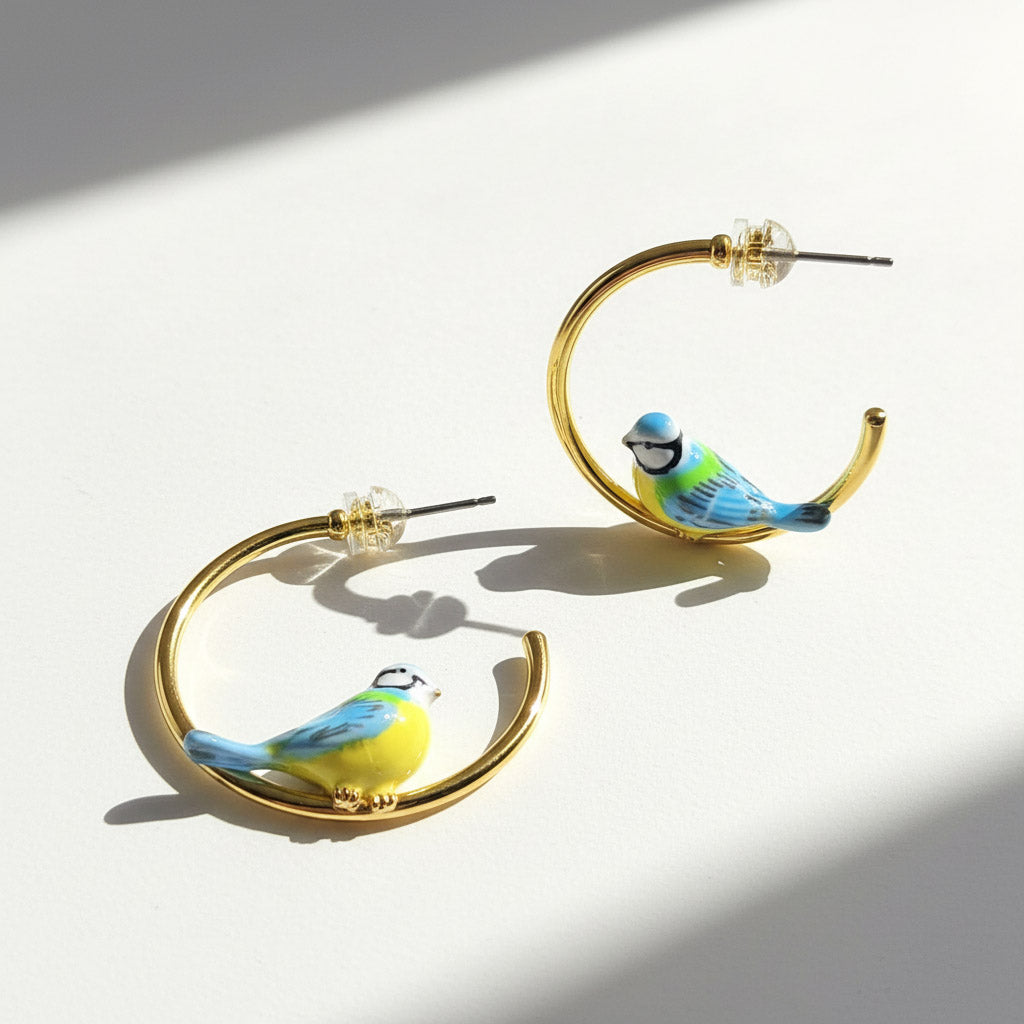 Gold hoop earrings with bird designs on a white background