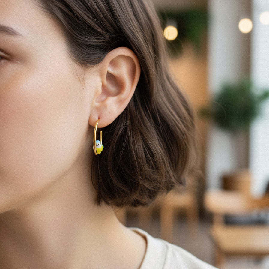 Close-up of a person wearing gold earrings with a blurred indoor background