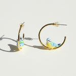 Gold hoop earrings with bird designs on a white background