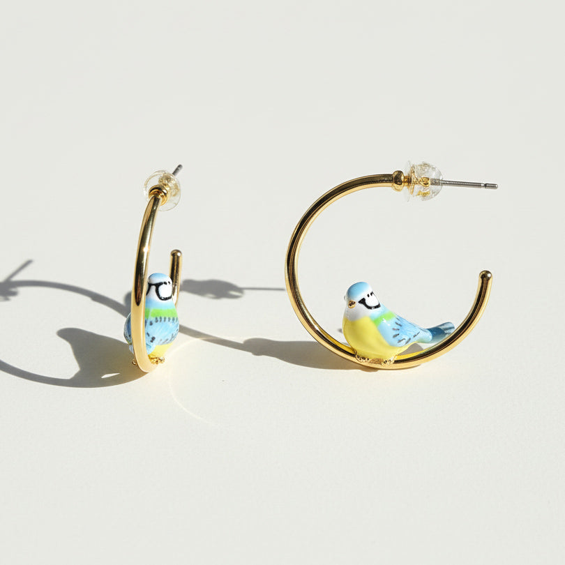 Gold hoop earrings with bird designs on a white background