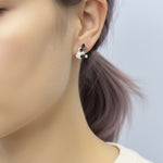 Close-up of an ear wearing a black and white earring with a blurred background
