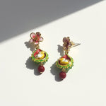 Colorful floral earrings with green, red, and gold details on a white background