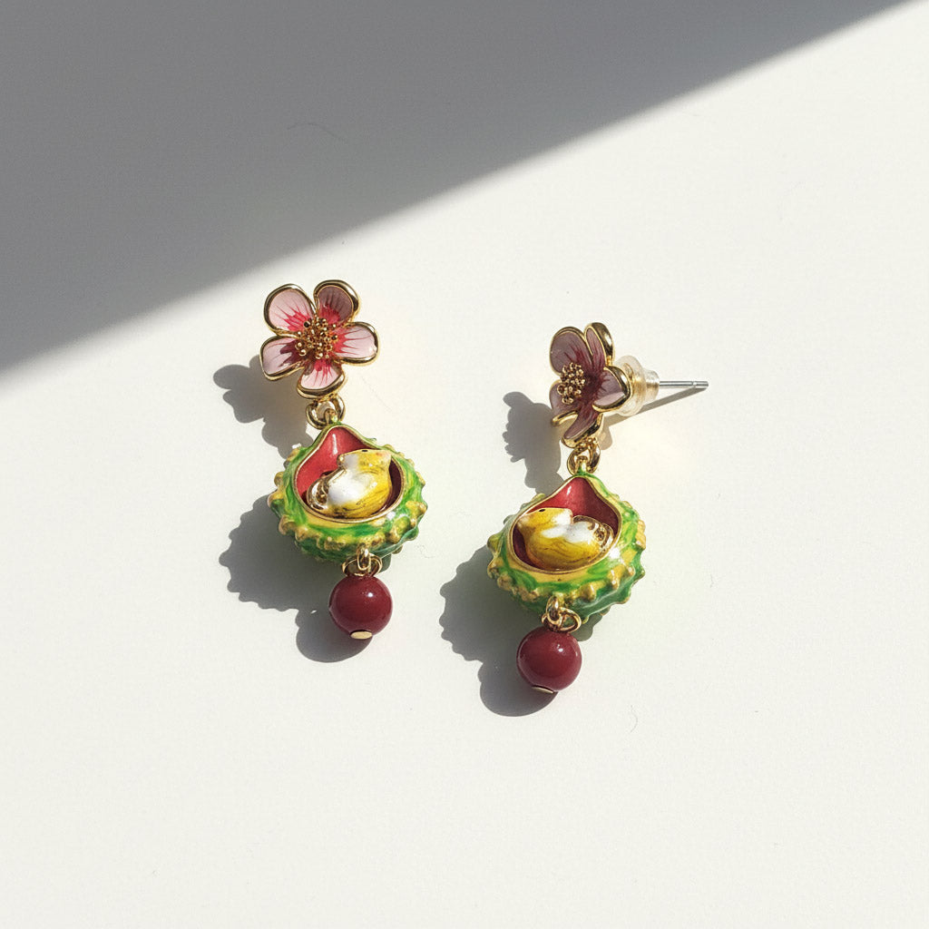 Colorful floral earrings with green, red, and gold details on a white background