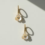 Gold hoop earrings with mother-of-pearl flower drops on white background